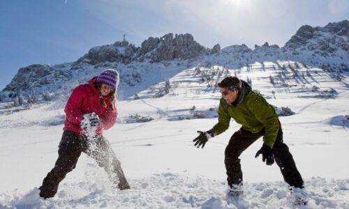 Winterwanderung mit Spaß im Schnee Zwei Personen auf einer Winterwanderung mit Single Aktiv Reisen lachen und genießen den frischen Schnee in verschneiter Berglandschaft.